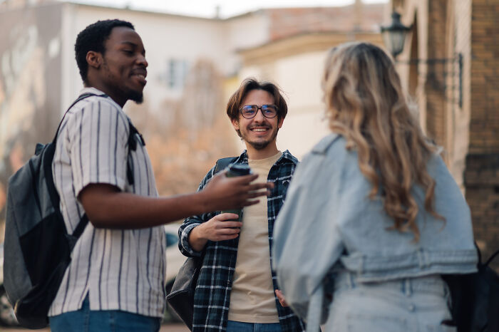 Three Americans chatting outdoors, smiling and enjoying a friendly conversation about great things in the US.