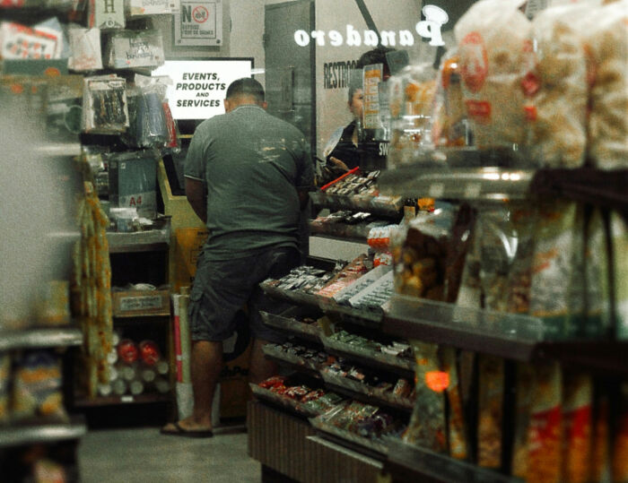 Man shopping inside a small grocery store aisle, highlighting everyday life and great things about the US.