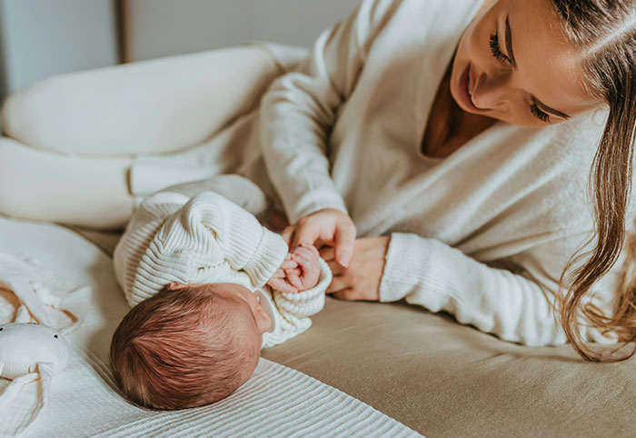 Young American expat mother gently holding her newborn baby, reflecting on cultural differences in Canada.