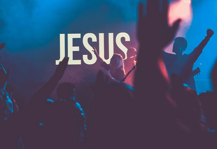 Crowd with raised hands at a concert with JESUS displayed, capturing an American expat experience in Canada event.