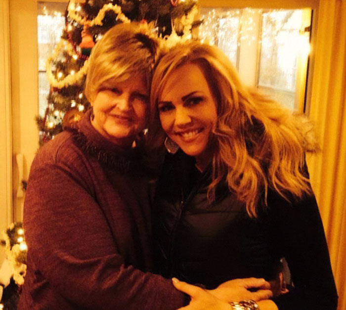 Former news anchor and her mother embraced warmly in a cozy home with a decorated Christmas tree in the background.
