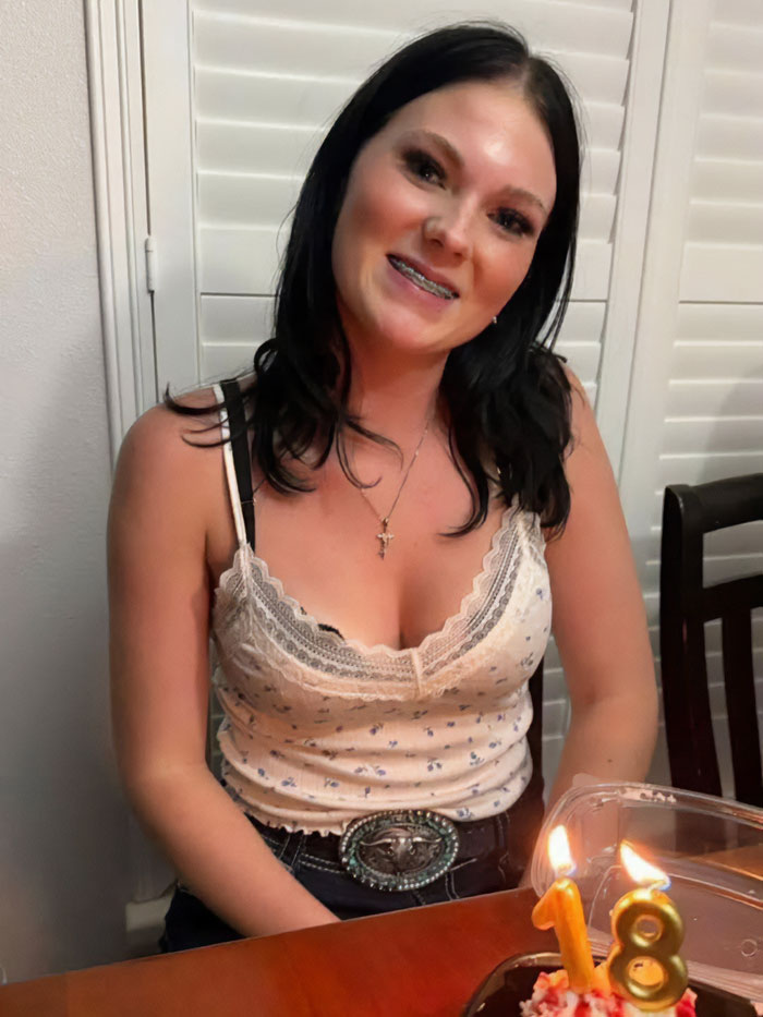 Young woman smiling at a table with birthday cake candles, relating to father of teen slain on cruise affair keywords.