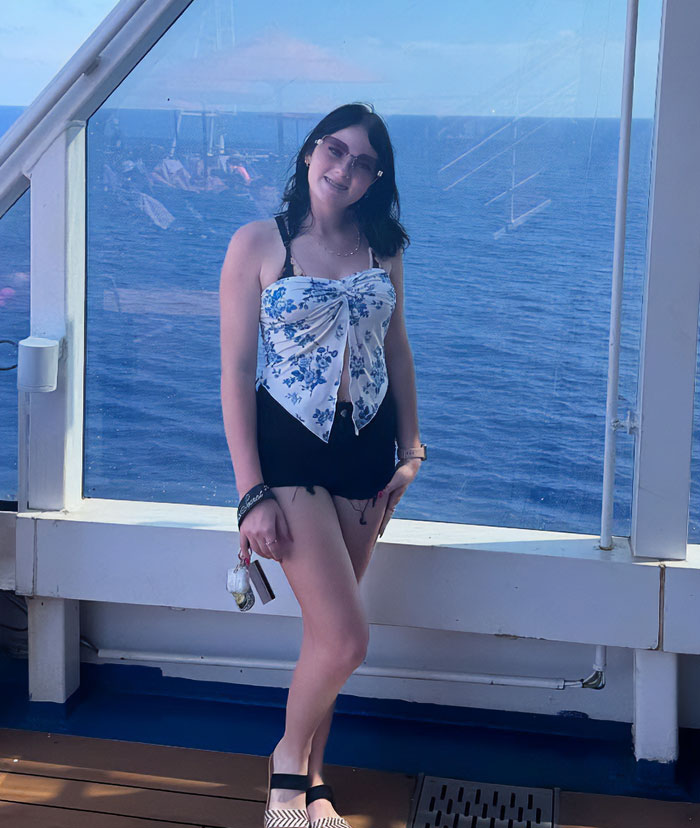Teen on cruise ship deck near railing with ocean background related to body found stuffed under cruise bed case.