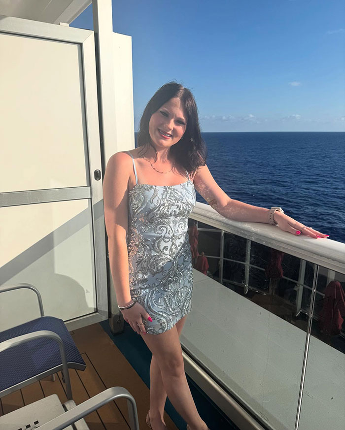 Young woman in silver dress on Carnival cruise balcony, related to stepsibling investigation after teen's body found under bed.