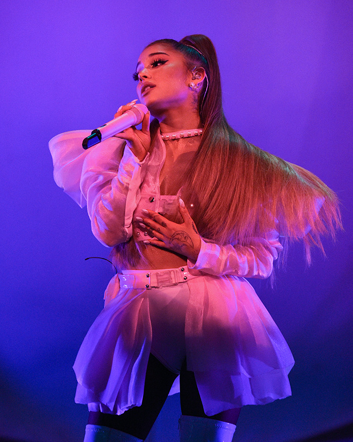Ariana Grande performing on stage with a microphone, highlighting her cryptic last hurrah announcement.