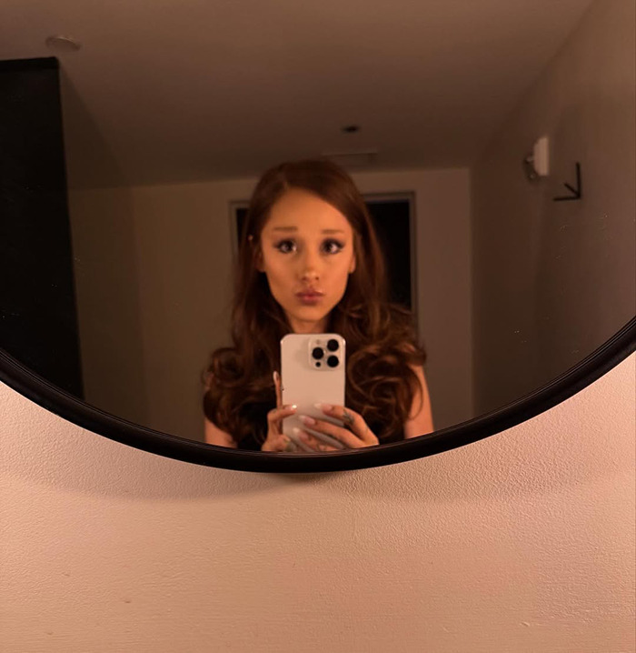 Ariana Grande taking a mirror selfie indoors, fans concerned Wicked role is affecting her energy and well-being.