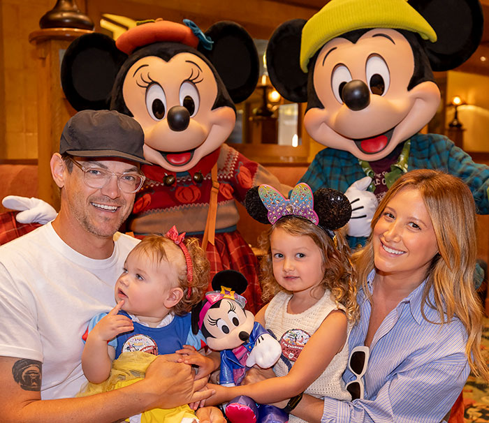 Ashley Tisdale with family at a theme park, smiling and holding children, highlighting Ashley Tisdale name change news.