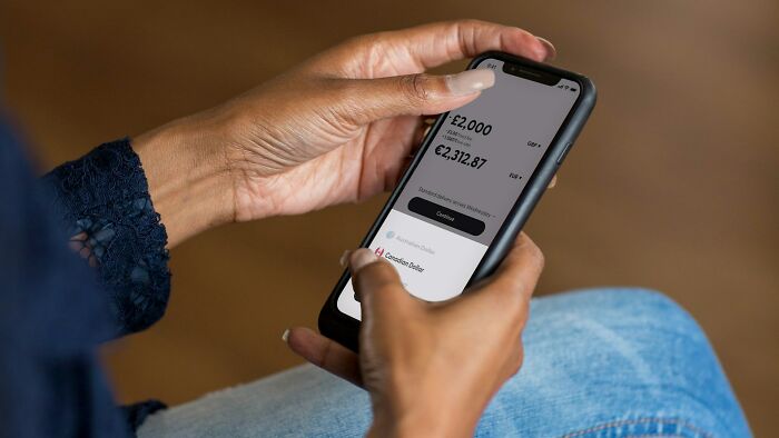 Person holding smartphone showing suspicious transaction details, illustrating times people fell for scams and consequences.