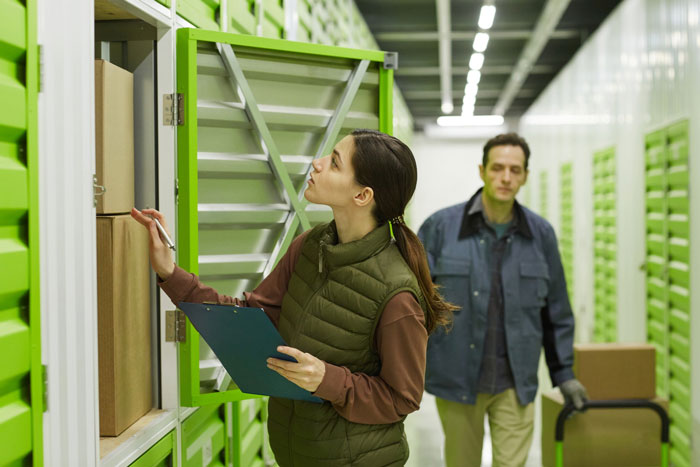 Woman organizing boxes and taking notes in a storage unit, illustrating aunt crib storage baby solutions and organization ideas.