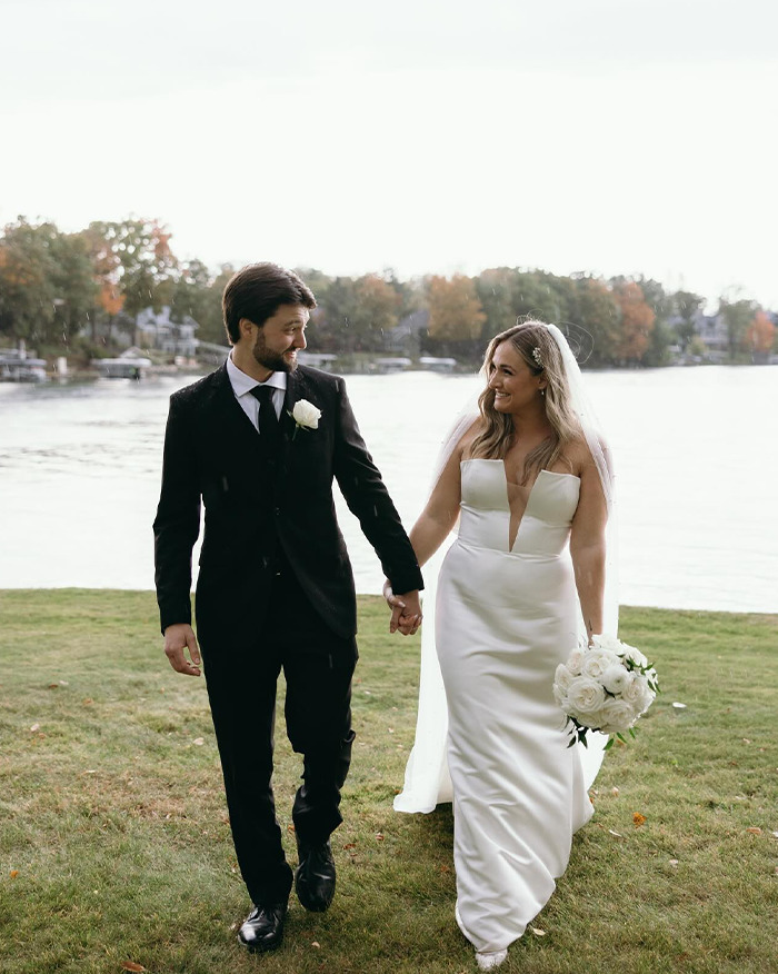 Newlywed couple holding hands by the lake, dressed in wedding attire, reflecting a chilling truth in autopsy findings.