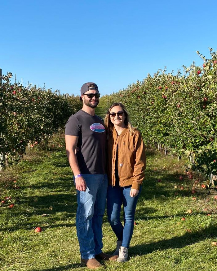Newlywed couple standing in an apple orchard on a sunny day, related to autopsy revealing chilling truth.