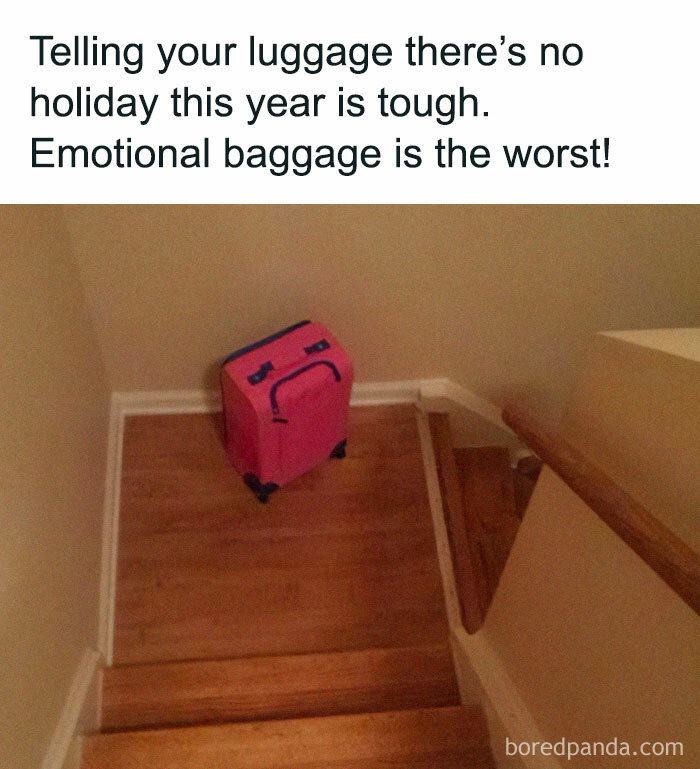 Pink suitcase with a sad face drawn on it at the bottom of wooden stairs, representing emotional baggage aviation meme.
