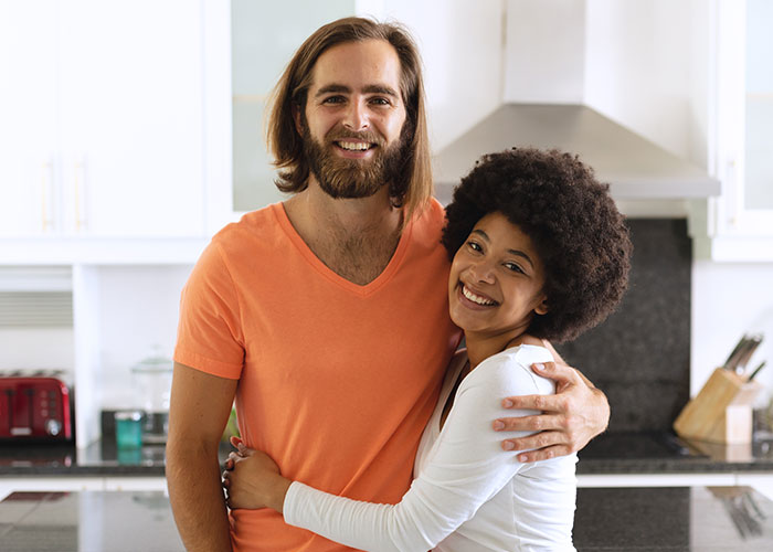 Smiling couple hugging in a modern kitchen, illustrating wild family dramas that make relatives look normal.