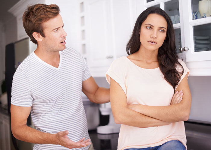 Couple in kitchen having a tense conversation illustrating wild family dramas making relatives look normal.