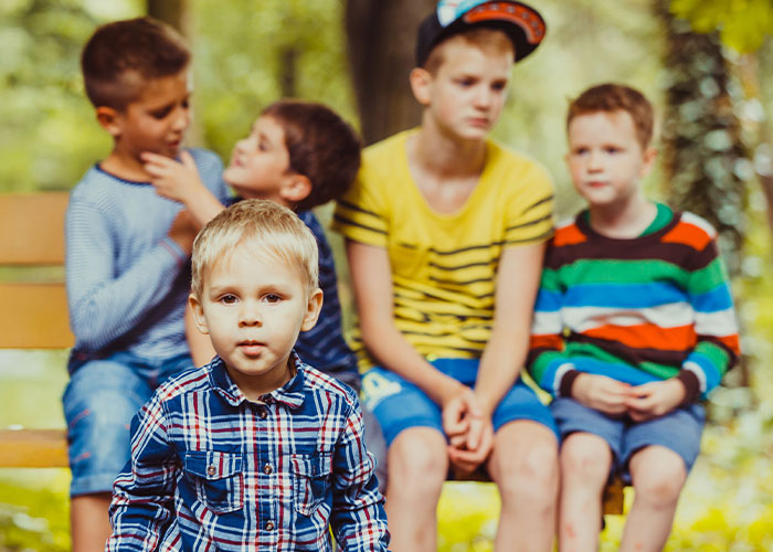 Group of young children outdoors with one boy in focus, illustrating wild family dramas among relatives in casual clothing.