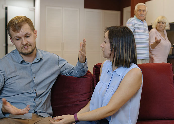 A young couple arguing on a couch with two older adults watching, illustrating wild family dramas and family conflicts.