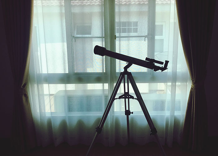 Telescope silhouetted against a window with curtains, illustrating crazy moments that weren’t what they looked like.