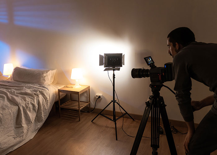 Photographer capturing a bedroom scene with lighting setup for crazy moments that weren’t what they looked like.