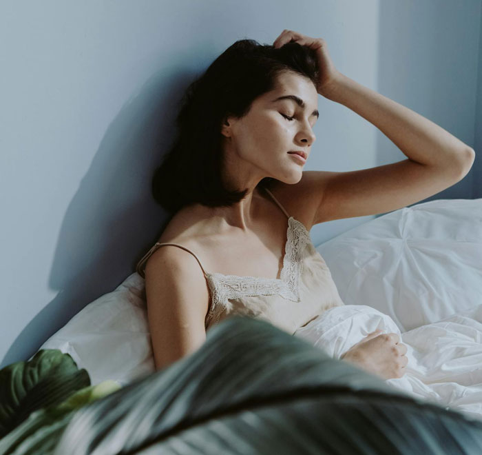 Woman lying in bed looking worried, illustrating mom's panic during overnight babysitting by a friend.