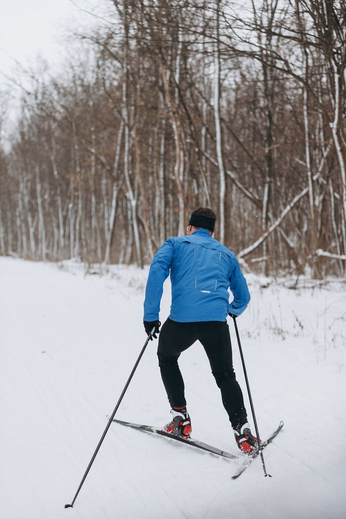 Man skiing through snowy forest trail wearing blue jacket and black pants in a scene showing craziest coincidences experienced.