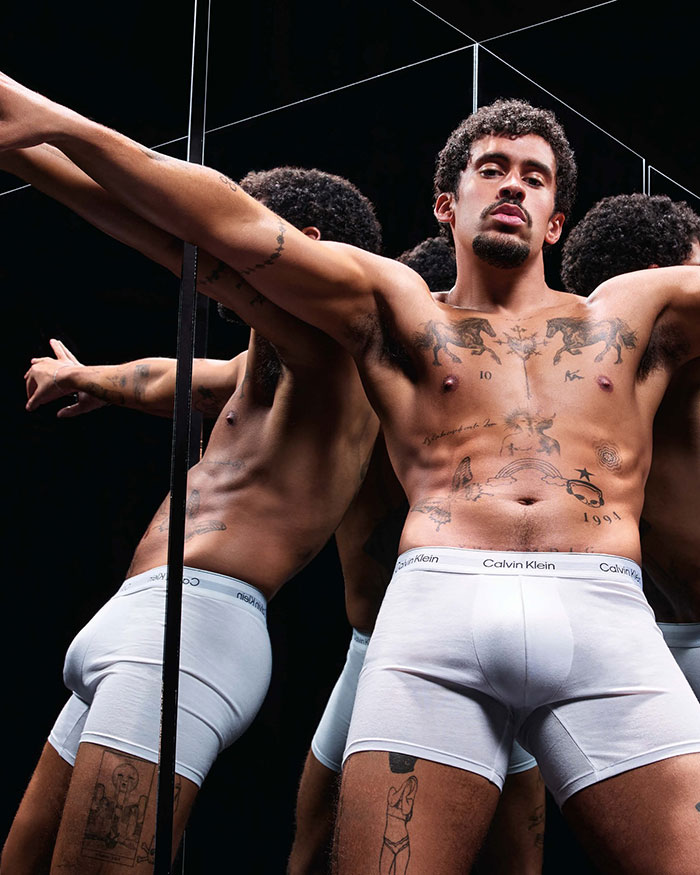 Male celebrity with tattoos posing shirtless in white Calvin Klein underwear, revealing more than expected in 2025 frenzy.