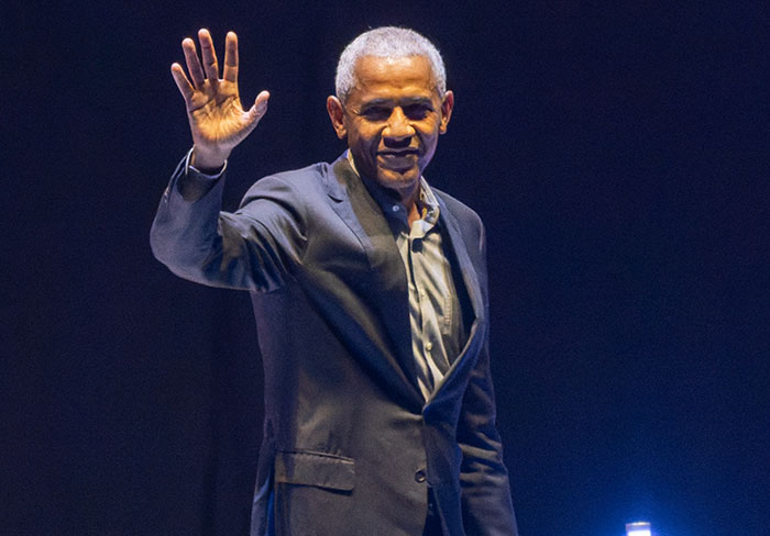 Barack Obama waving on stage during an emotional event honoring war veterans and their reactions.