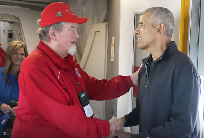 Barack Obama greeting a war veteran on a plane, sharing a heartfelt moment with veterans on board.