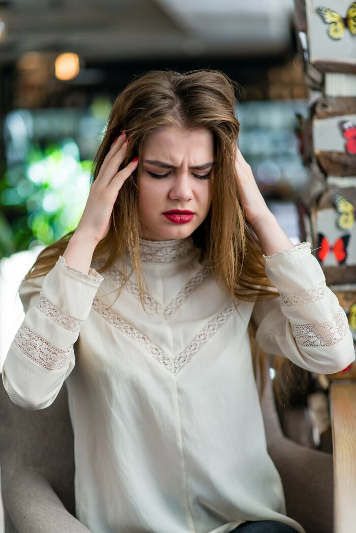 Stressed young woman holding her head in frustration representing worst things seen on Black Friday by employees.
