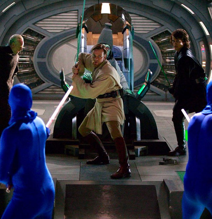 Behind-the-scenes photo of actors in costume holding lightsabers ready for a staged action scene on set.