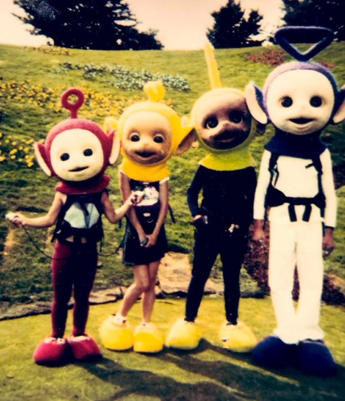 Four people wearing unhinged behind-the-scenes costumes resembling characters outdoors on a grassy slope.