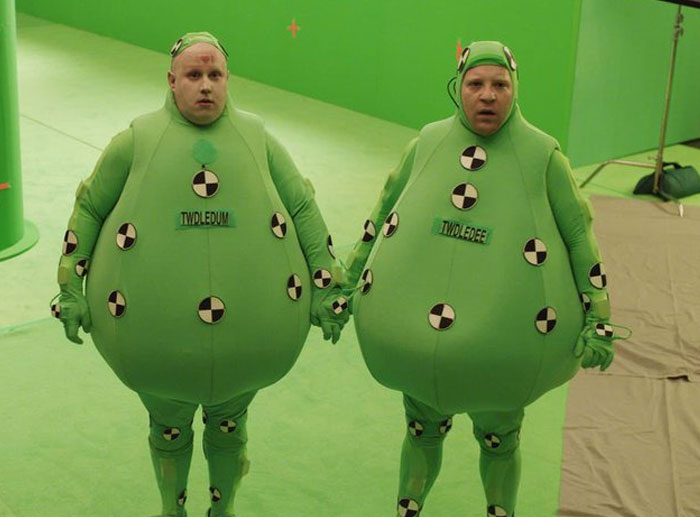 Two actors in unhinged behind-the-scenes photos wearing green motion capture suits on a film set with a green screen background.