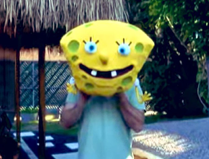 Person wearing a large unhinged SpongeBob head mask outdoors in a behind-the-scenes photo meme moment.