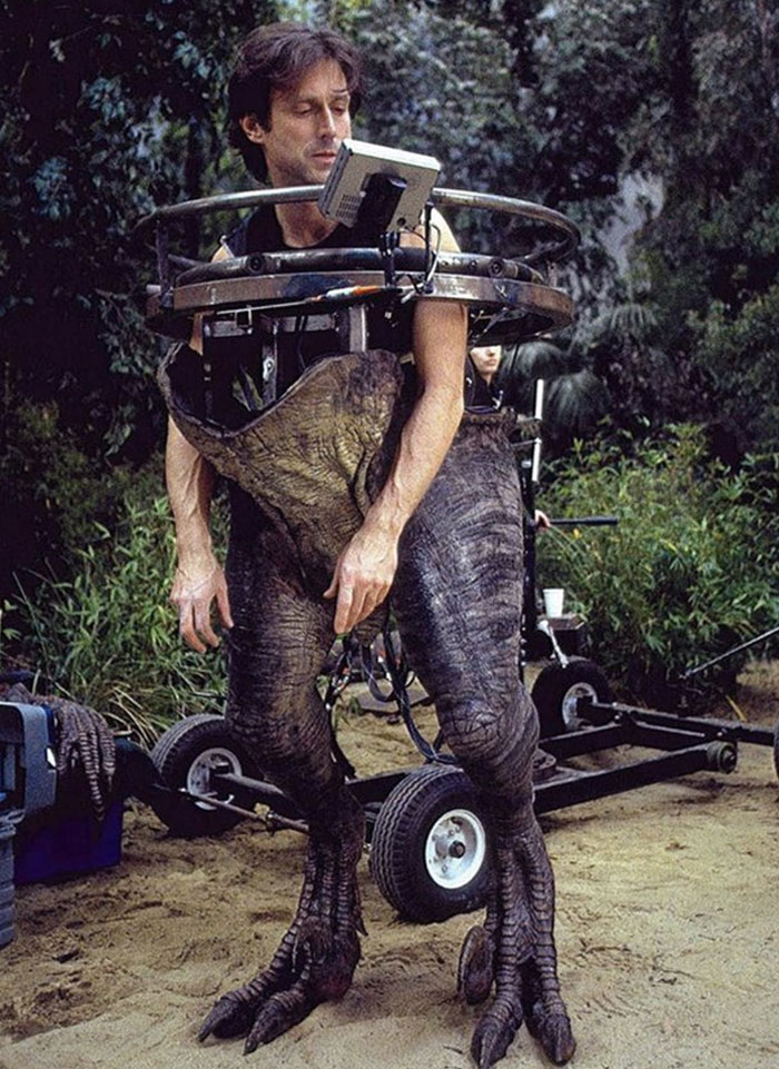 Actor in dinosaur costume on set, captured in unhinged behind-the-scenes photo perfect for meme creation.
