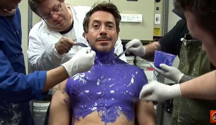 Robert Downey Jr. having purple body paint applied by several crew members in unhinged behind-the-scenes photos.