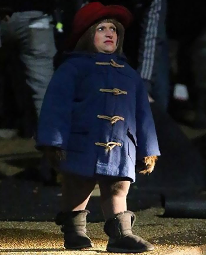 Person dressed in a blue coat and red hat on set, captured in an unhinged behind-the-scenes photo meme moment.