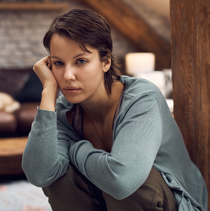 Young woman sitting indoors looking thoughtful and pensive, reflecting emotions of best friend no contact returns situation.