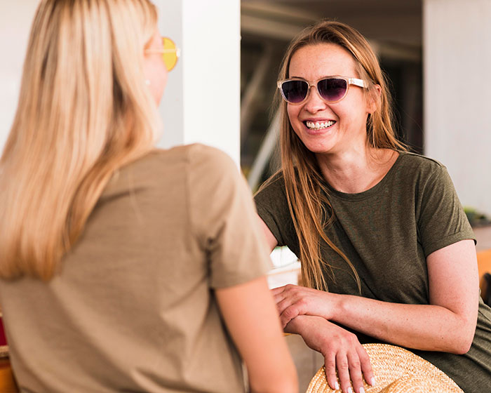 Two women smiling and chatting while sitting together, depicting a best friend no contact returns moment.