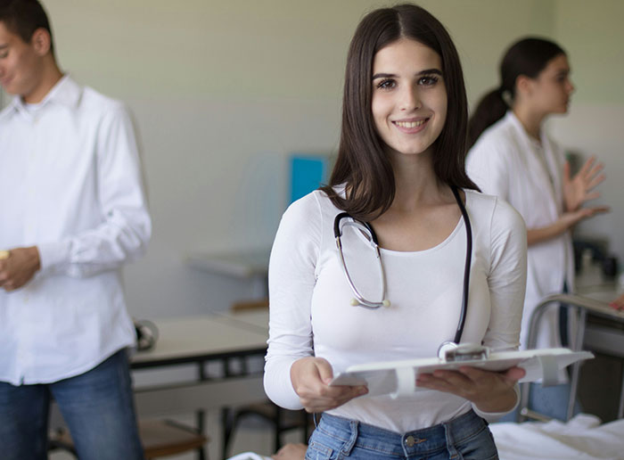 Young woman with stethoscope smiling while holding a clipboard, representing people who got truly lucky moments.