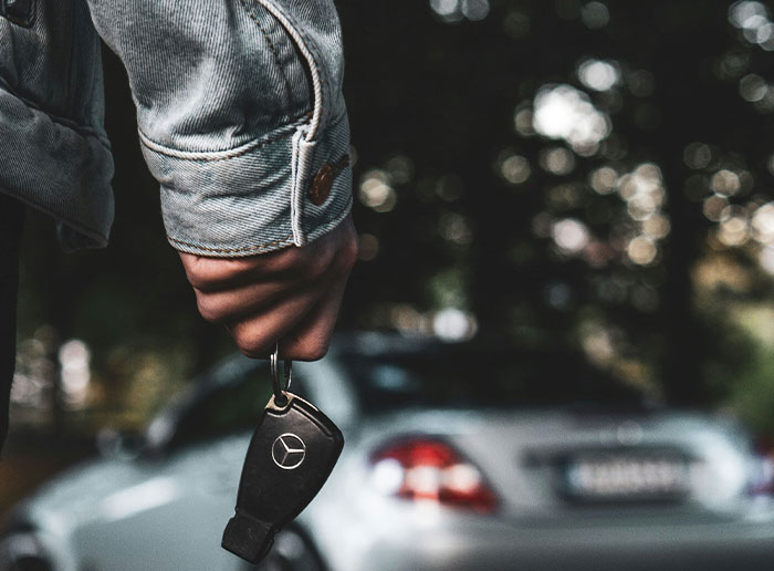 Person holding car key with blurred luxury car in the background, symbolizing moments when people got truly lucky.