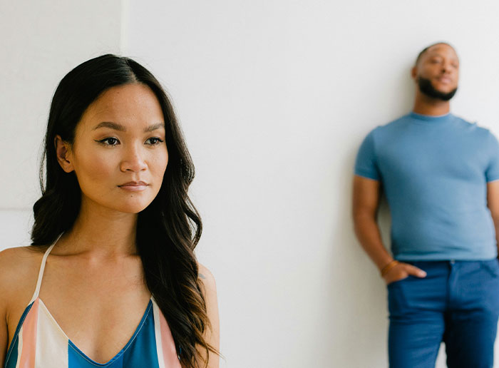 Woman looking thoughtful in foreground with man blurred in background, capturing moments of people getting truly lucky.