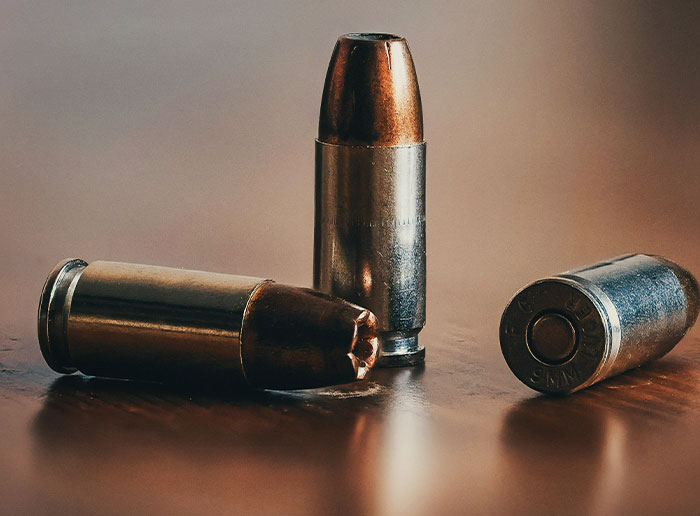 Three copper-colored bullets on a wooden surface symbolizing the bullet I dodged and moments of luck.