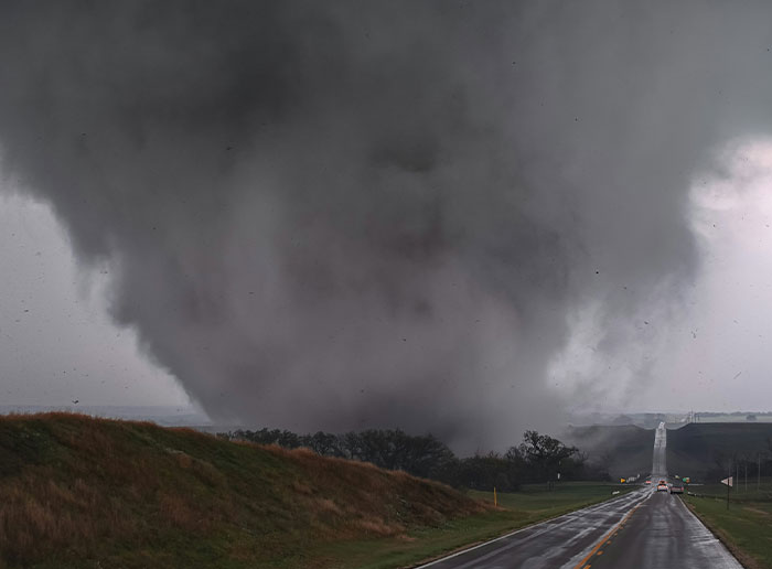A massive tornado approaching a rural road with dark storm clouds, capturing a moment of people getting truly lucky.