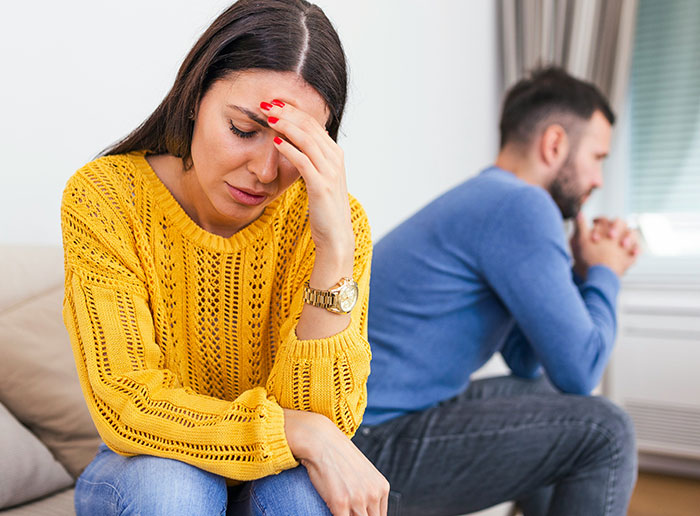 Woman looking upset and man sitting back to back, illustrating moments people got truly lucky avoiding conflict and heartbreak.