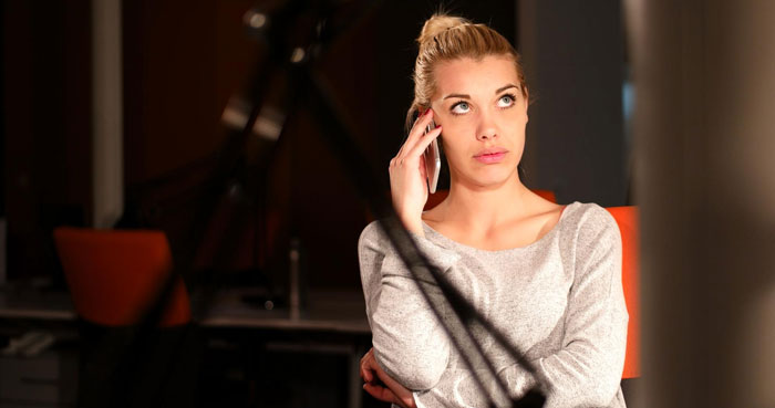 Polyamorous woman making a pass on phone, looking frustrated indoors, capturing tension in a modern setting.
