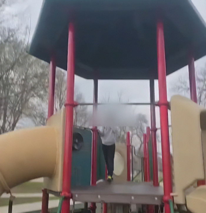 Playground structure with blurred figure, related to viral mom who called autistic boy the N-word facing trial.