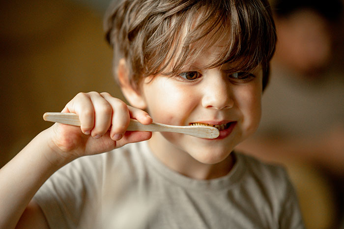 Young boy brushing his teeth indoors, highlighting a family setting during a power trip and Halloween conflict with stepmom.