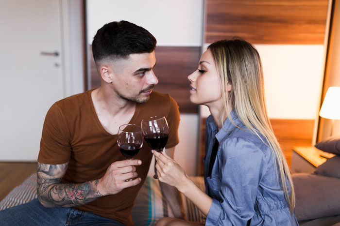 Couple sharing wine on vacation, the woman looking suspicious as the boyfriend appears distracted and unfaithful.