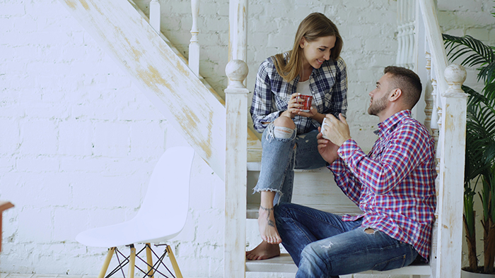 Couple having a serious conversation on stairs about financing a renovation and marriage appearing like a transaction.