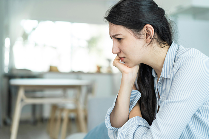 Young woman looking worried and thoughtful indoors, reflecting on boyfriend's demand about marriage and home renovation finance.