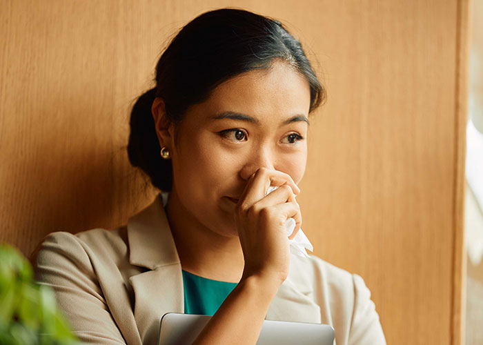 Young woman reflecting thoughtfully by a wooden wall, symbolizing a new life and success in France after leaving the US.
